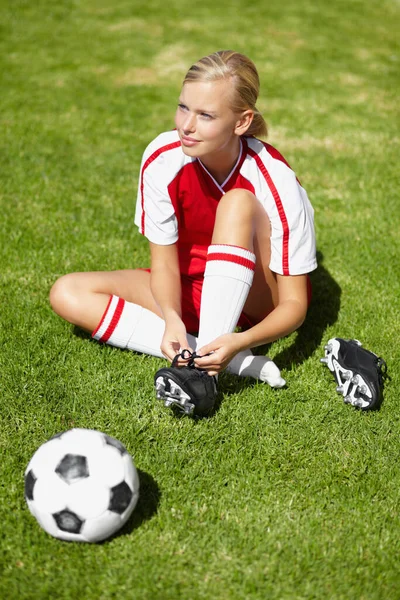 准备参加比赛吧 一个女足球运动员躺在草地上把鞋子捆起来 — 图库照片