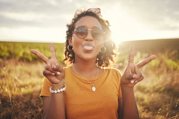 Nature, freedom and peace hand sign by woman at sunset in the countryside, happy and content while traveling, Portrait, grass and black woman having fun on road trip, taking break in rural landscape.