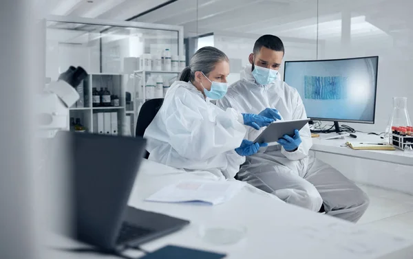 Covid research, tablet and science with a man and woman scientist working in a lab for innovation and healthcare. Medical, internet and analytics with a medicine team at work in a laboratory.