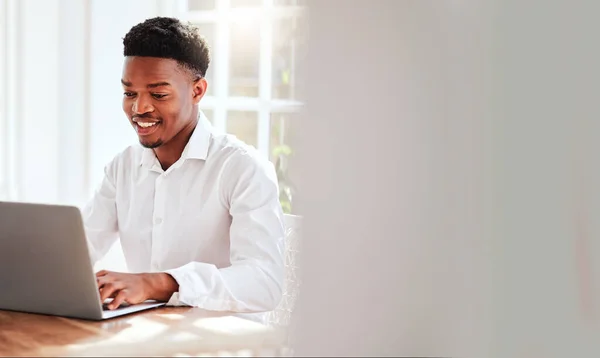 Internet, laptop and black man working in home office, happy freelance worker at desk. African startup businessman with smile, technology and online project for social media management company.