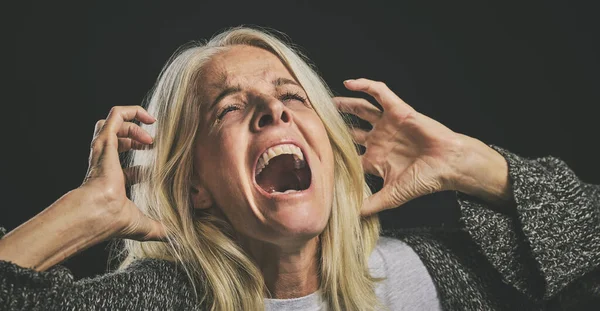 Screaming senior woman, mental health and depression from bipolar anxiety, stress and scary fear on black background. Schizophrenia, psychology and crazy person shout, drugs problem and epilepsy risk.