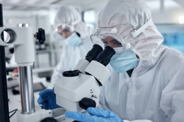 Bilimsel yenilik, araştırma ve geliştirme için mikroskop araştırması yapan PPE, covid ve DNA bilimcisi bir test laboratuvarında. Analiz yapan ya da laboratuarda tıbbi örnek inceleyen biyoteknoloji çalışanları..