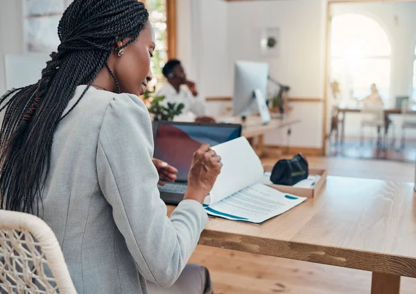 Paperwork, office and black business woman reading corporate company documents at her desk in the workplace. Professional, young and african leader or manager working on a management strategy report