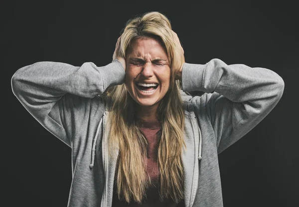 Stress, screaming or crying woman with hands over ears on black background in studio with mental health, anxiety or schizophrenia. Psychology, depression or shouting patient in counseling help asylum.