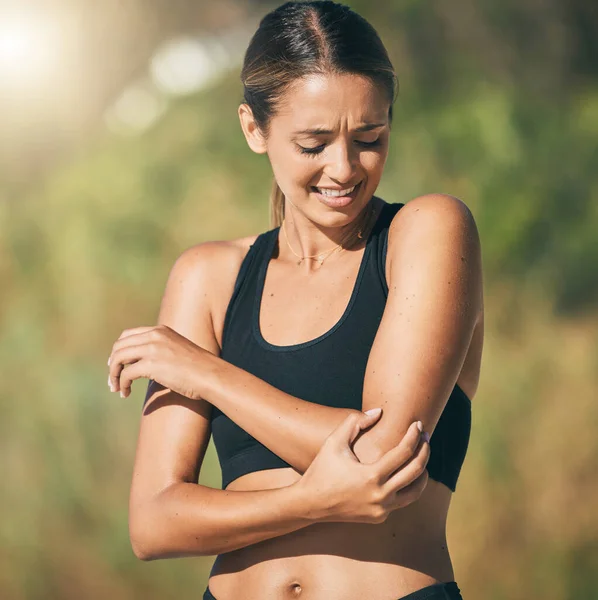 Fitness, woman and elbow in pain, injury or sports accident of runner suffering in joint ache outdoors. Athletic female holding painful area of muscle, inflammation or broken bone in discomfort.