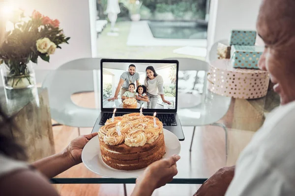 Video call, birthday and cake with a family on a laptop screen for celebration of a senior party at home. Candle, communication and love with an elderly man and woman on call with their relatives.