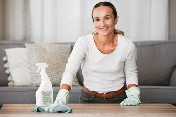 Woman cleaning home, table and living room with a chemical disinfectant soap spray bottle to clean house dirt. Adult housekeeping with a smile, family room is healthy and hygienic or germ free life.