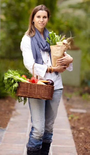 Armed with healthy, fresh goodness. Attractive woman holding a paper bag of fresh produce while standing outside