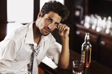 Work hard to wind down - Fast-paced Professional. A handsome young man winding down after work with a drink at the bar clipart