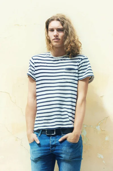 Making indie style his own. Young man with long ,curly hair and a casual sense of style