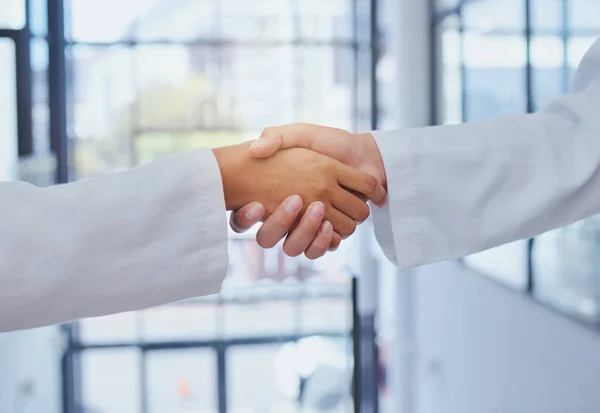 Doctors meeting, shaking hands and partner at hospital with lab coats. Scientist or doctor agree on medical business, support and cooperate together with handshake to show collaboration and teamwork.