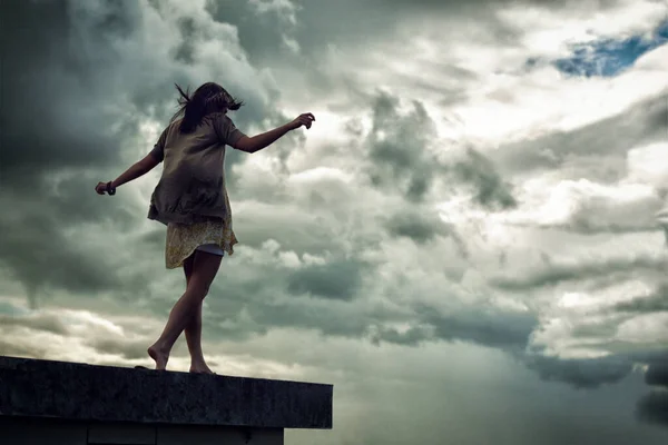 端を歩く 腕を伸ばして屋上を歩く若い女性 — ストック写真