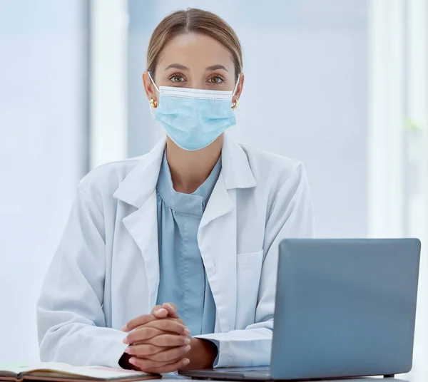 Covid, laptop telehealth and doctor face mask for healthcare, safety and insurance in medical clinic. Portrait woman, wellness expert and therapist consulting online in corona virus pandemic hospital.