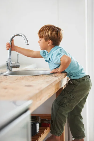 Musluğa Ulaşmak Için Mutfak Tezgahına Tırmanan Tatlı Bir Çocuk — Stok fotoğraf