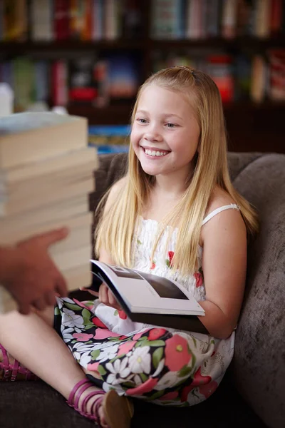 她是个小书虫 一个可爱的金发碧眼的小女孩笑了 这时有人把一叠书带到图书馆 — 图库照片