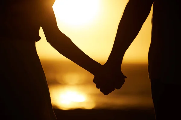日没時にビーチで夫婦の手 カップルのシルエットは ビーチで手を握っている カップルの休日の海で結合します 海による休暇における関係のカップル — ストック写真