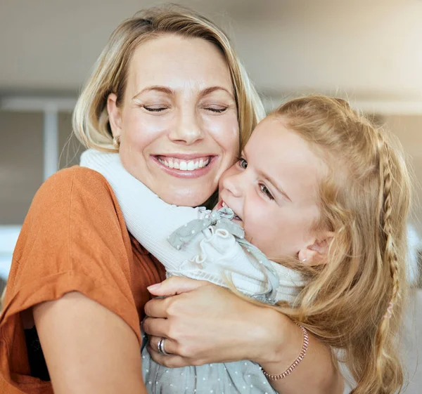 A happy family of two relaxing in the lounge and sitting on the couch together. Loving caucasian single parent bonding with her daughter while relaxing on a sofa at home.