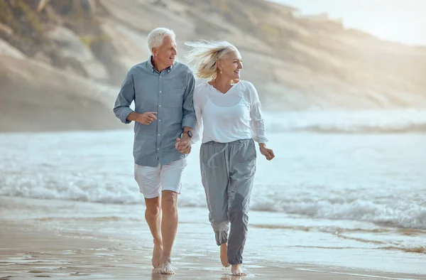 A happy mature caucasian couple enjoying fresh air on vacation at the beach. Smiling retired couple getting a cardio workout while walking outside.