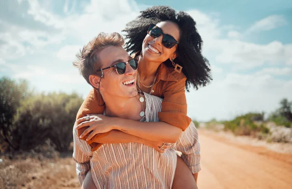 Love, happy and couple piggy back on road path in Arizona desert in USA for romantic getaway. Interracial people dating smile while enjoying summer romance on travel holiday adventure together