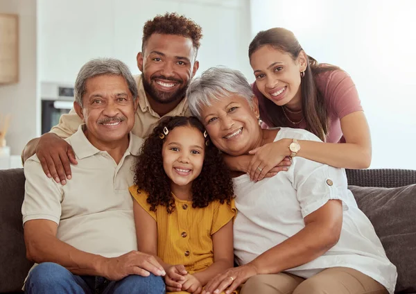 Portrait of mixed race family with child enjoying weekend in living room at home. Adorable smiling hispanic girl bonding with grandparents, mother and father. Happy couples and child sitting together.