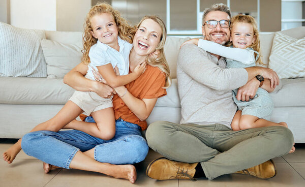 A happy Caucasian family of four relaxing in the living room at home. Loving smiling family being affectionate on the lounge floor. Young couple bonding with their little kids at home.