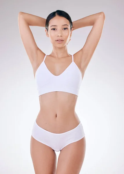 Portrait of a beautiful young mixed race model posing seductively in underwear against a grey studio copyspace background. Confident hispanic woman showing her curvy shape and smooth hairless skin.
