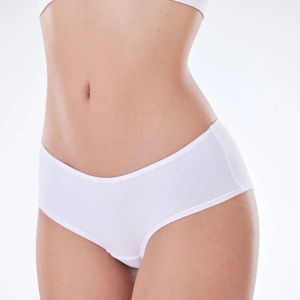 Closeup of unrecognizable mixed race models hairless body and slim waist posing against a white copyspace background. Unknown Hispanic woman feeling fresh while showing her healthy belly and skin.