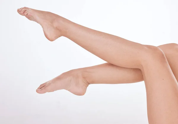 Closeup of unrecognizable woman posing against a white studio background. One female only feeling confident while showing her hairless, smooth legs after hair removal or epilation.