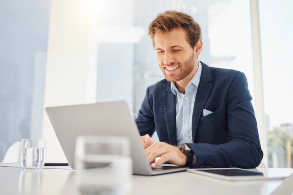 One happy young caucasian businessman working on a laptop in an office. Confident male entrepreneur planning while browsing the internet and sending emails to clients. Man joining a virtual conferenc.
