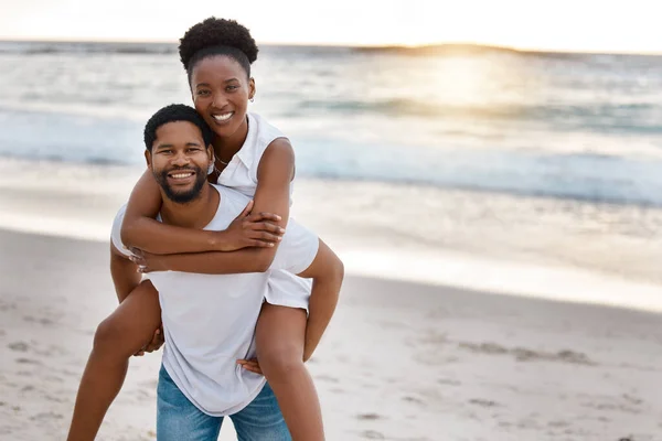 若い幸せなアフリカ系アメリカ人のカップルが一緒に海で一日を過ごす 陽気なボーイフレンドは彼のガールフレンドにビーチでピギーバックを与える 夫と妻を愛する海岸沿いの絆 — ストック写真