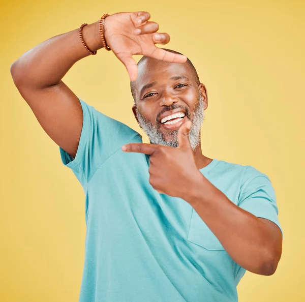 Portrait of a happy mature african man making a frame gesture with his hands against a yellow studio background. Life is full of happy moments and we should try and capture it one frame at a time