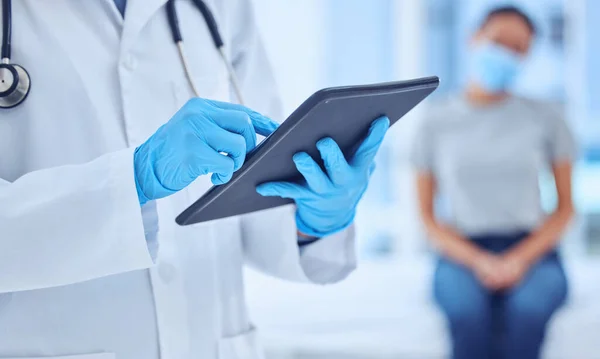 Hands of doctor using a digital tablet in checkup. Physician checking patient covid test results on wireless device. Closeup on hands of gp using online digital device in checkup.