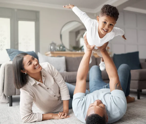 A happy mixed race family of three relaxing on the lounge floor and being playful together. Loving black family bonding with their son while playing fun games on the carpet at home.