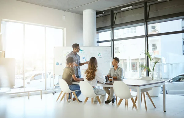 Group of diverse businesspeople having a meeting in an office at work. Young african american businessman talking while doing a presentation for coworkers.