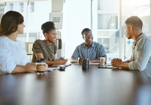 Group of diverse businesspeople having a meeting in an office at work. Happy mixed race businessman talking during a workshop at a table with coworkers. Businesspeople planning together.