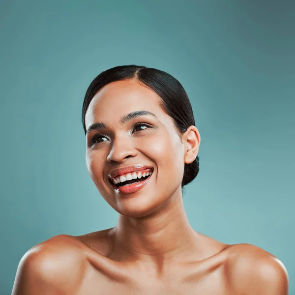 A young beautiful mixed race woman with smooth soft skin posing and smiling against a green studio background. Attractive Hispanic female with stylish makeup posing in studio.