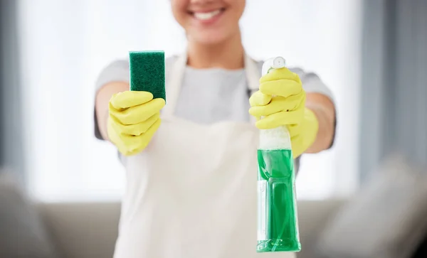 One unrecognizable woman holding a cleaning product and sponge while cleaning her apartment. An unknown domestic cleaner wearing latex cleaning gloves.