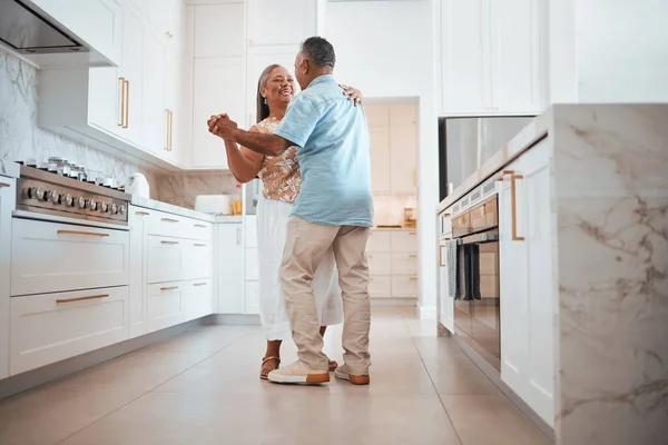 Couple, elderly and dance in kitchen for love, romance and happy together while home in retirement. Senior, man and woman do fun dancing in house for bonding, happiness and care with smile on face.