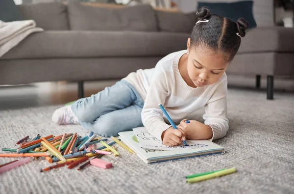 可爱的混血儿躺在客厅的地毯上做作业 儿童涂色以及在家里表现出艺术和创造力 — 图库照片