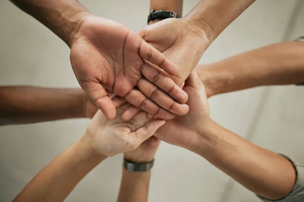 Close up of stacked hands. Group of colleagues putting hands together in the office. Creative team joining hands and showing unity through teamwork.
