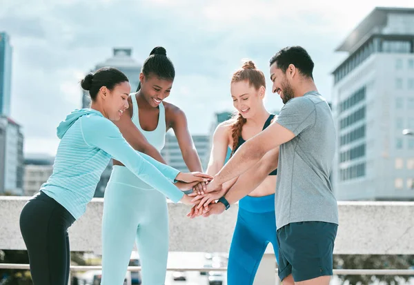 Diverse group of happy sporty people stacking hands together in pile to express unity and support. Motivated athletes huddled in circle for encouraging workout pep talk. Joining for collaboration, te.