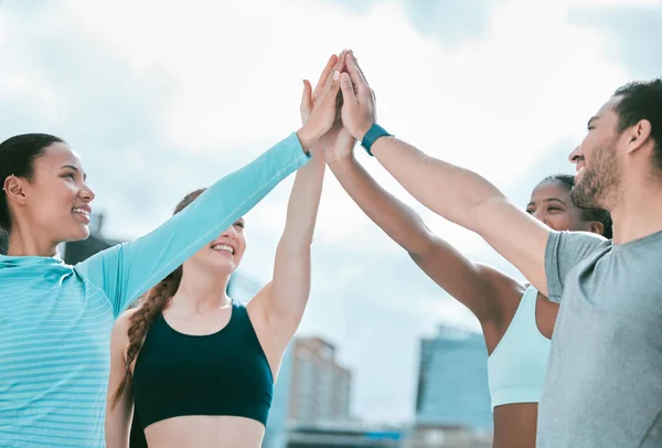 Diverse group of happy sporty people joining hands to high five for celebration of unity and support. Motivated athletes huddled for workout encouragement. Merging for collaboration, team spirit and .