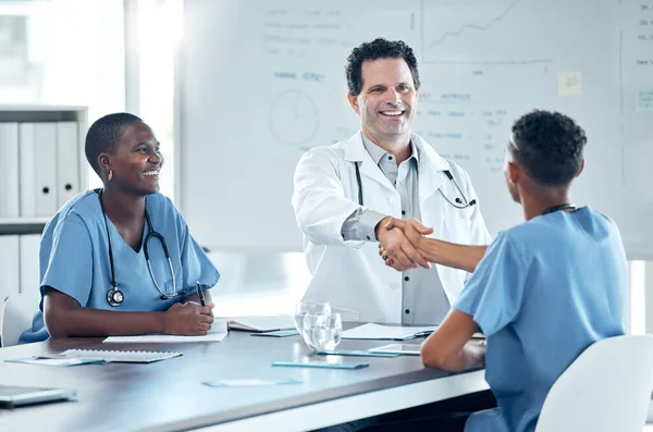 Handshake, meeting and doctor shaking hands with nurse to welcome him on the job after a promotion in a hospital. Healthcare worker saying thank you to a medical expert for helping in surgery success.