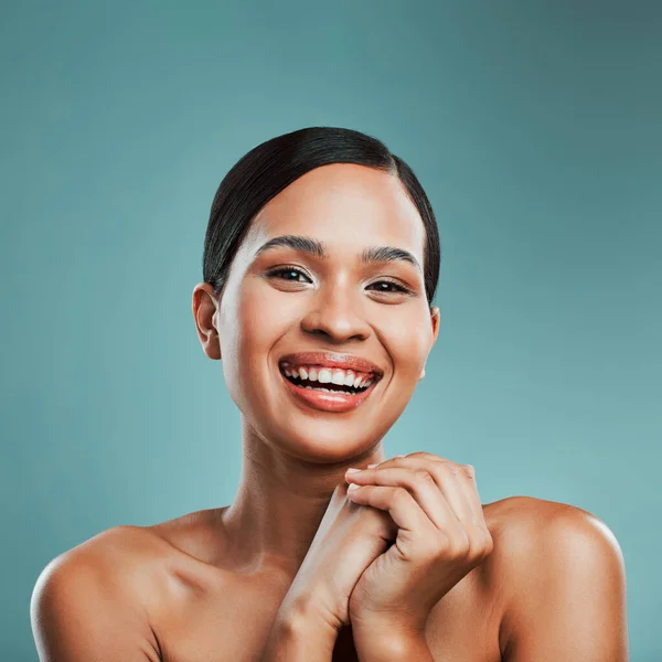 Portrait of a young beautiful mixed race woman with smooth soft skin posing and smiling against a green studio background. Attractive Hispanic female with stylish makeup posing in studio.