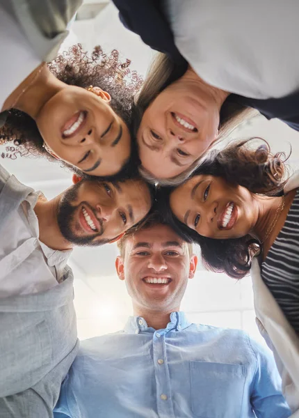 Group of joyful diverse businesspeople huddling together in support and unity together at work. Happy business professionals joining their heads in a meeting.