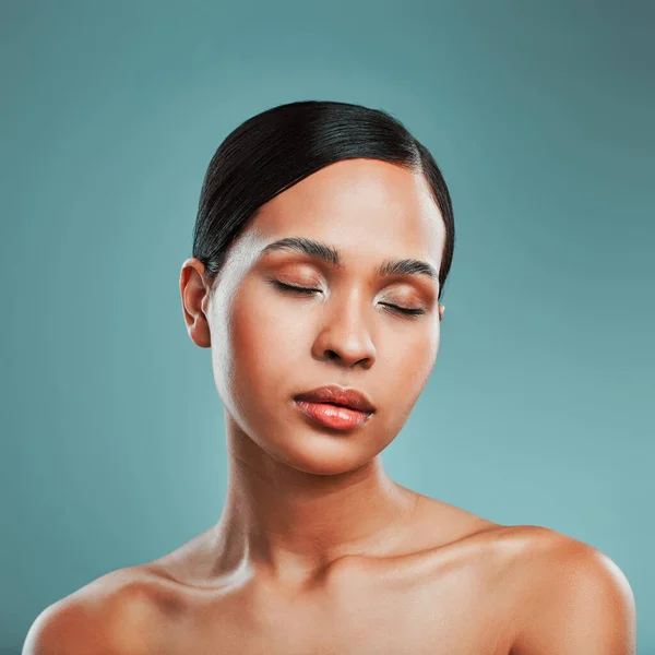 Portrait of a young beautiful mixed race woman with smooth soft skin posing against a green studio background. Attractive Hispanic female with stylish makeup posing in studio.