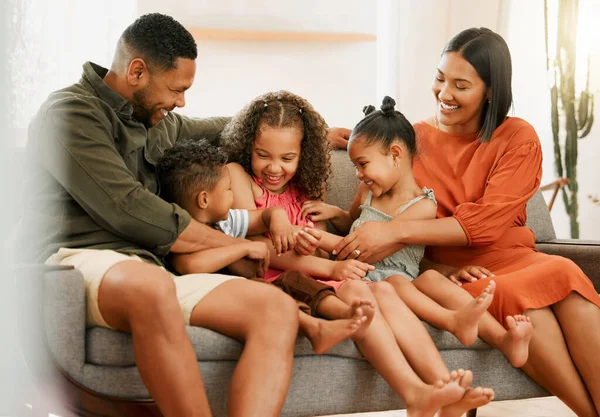 A happy mixed race family of five relaxing on the sofa at home. Loving black family being playful on the sofa. Young couple bonding with their foster kids at home.