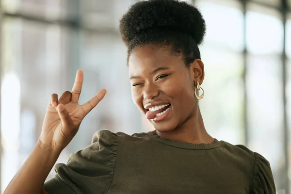 Happy excited african american professional showing peace sign and showing tongue. Playful young business woman entrepreneur showing victory sign in an office.