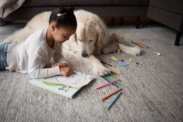 Douce Petite Enfant Métissée Faisant Ses Devoirs Tout Étant Allongée — Photo