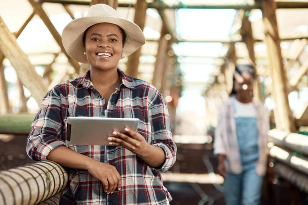 Happy farmer using a digital tablet. African american farmer using a digital device. Portrait of a smiling farmer standing in a greenhouse. farm worker holding wireless tech device